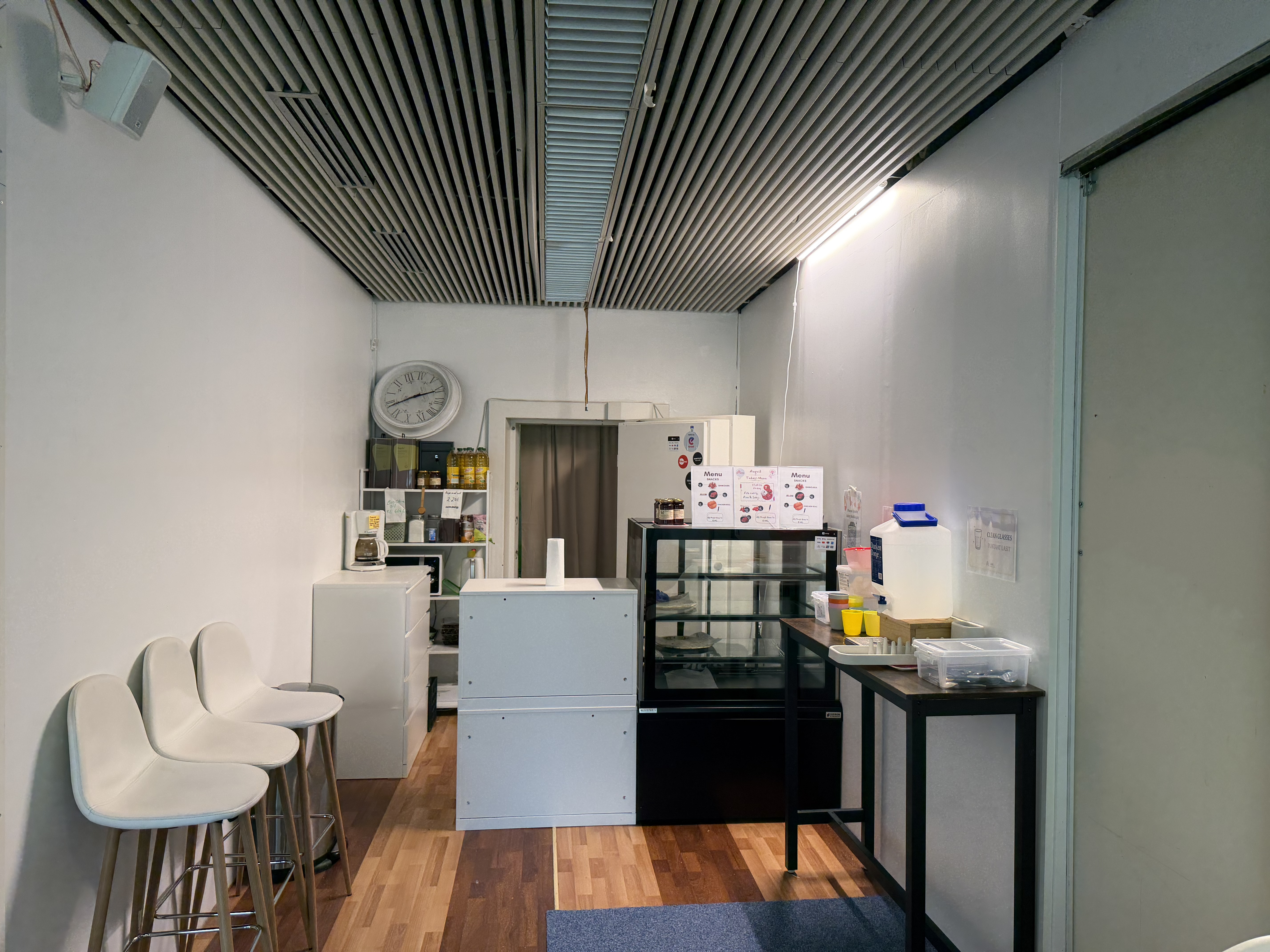 A pantry and snack-prep area at EMC's business lounge, with a coffee maker, honey jars, and menu signs